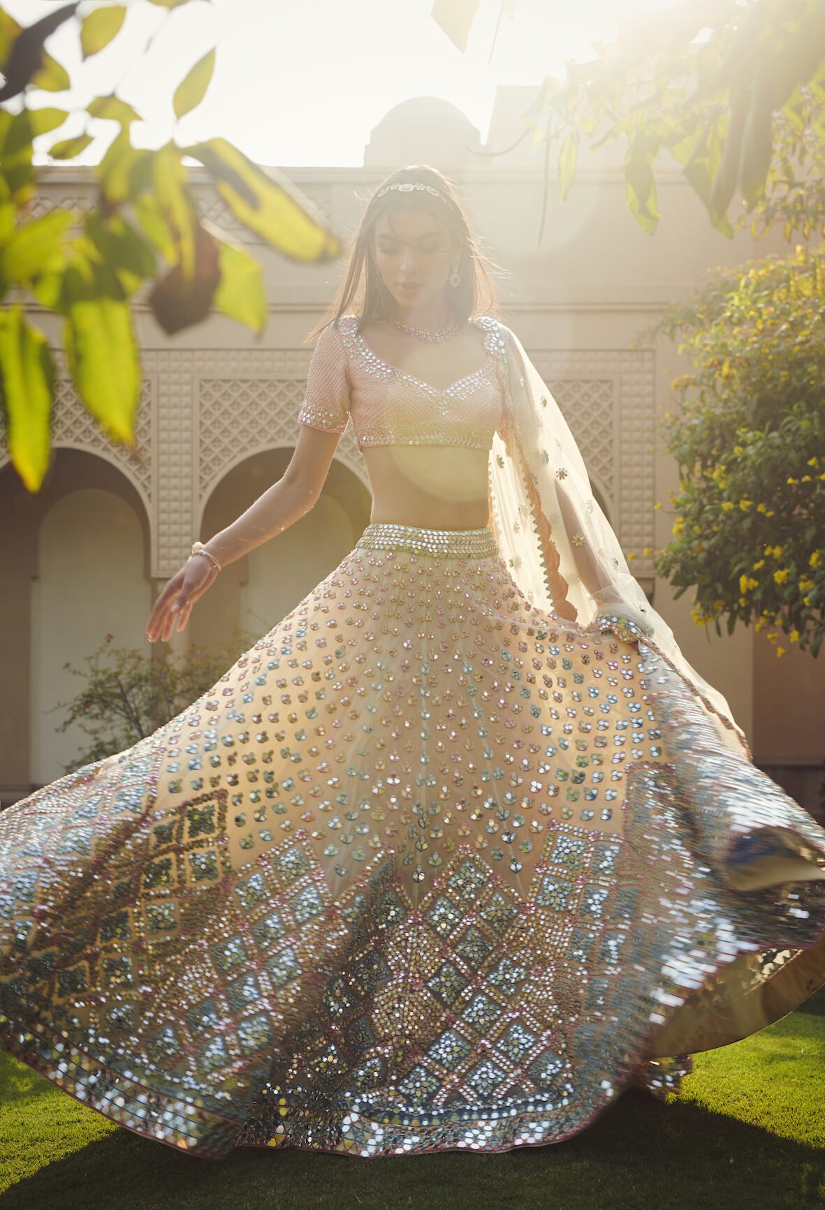 Bride twirling in a mirrorwork lehenga in a sunlit palace courtyard