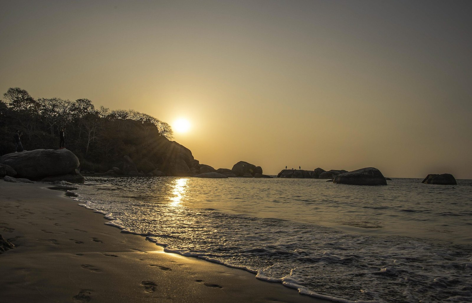 Golden sunset over the rocks and gentle surf of Agonda Beach, South Goa