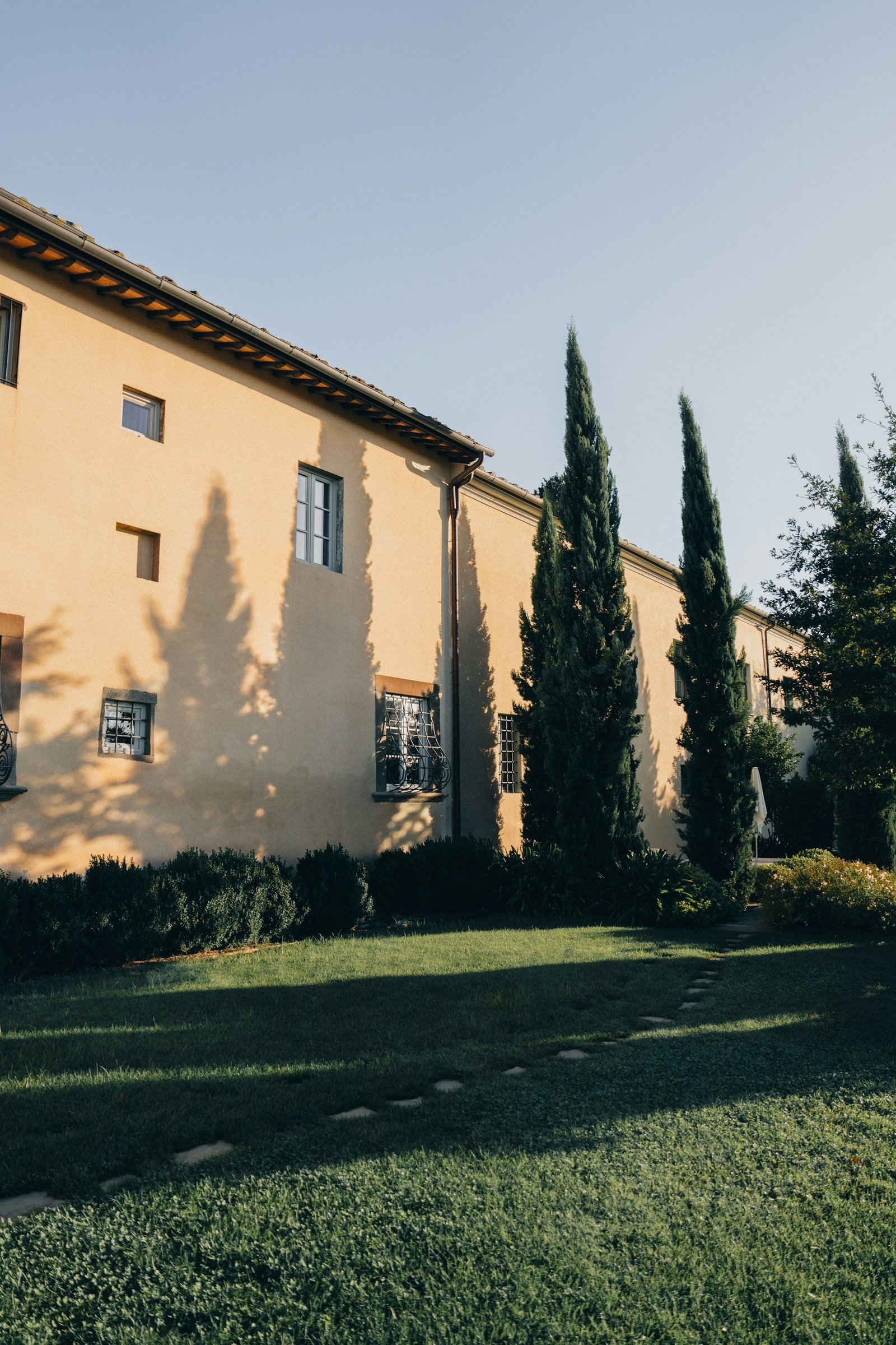 A Tuscan villa framed by cypress trees in golden evening light