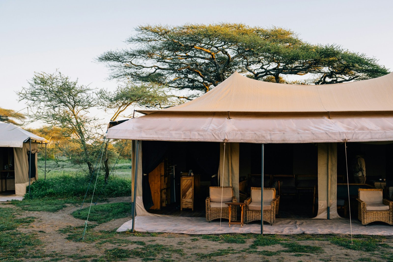 An elegant luxury safari tent with a furnished private veranda at dusk